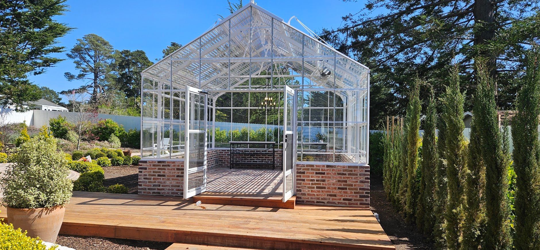 A greenhouse is surrounded by trees and bushes in a garden.
