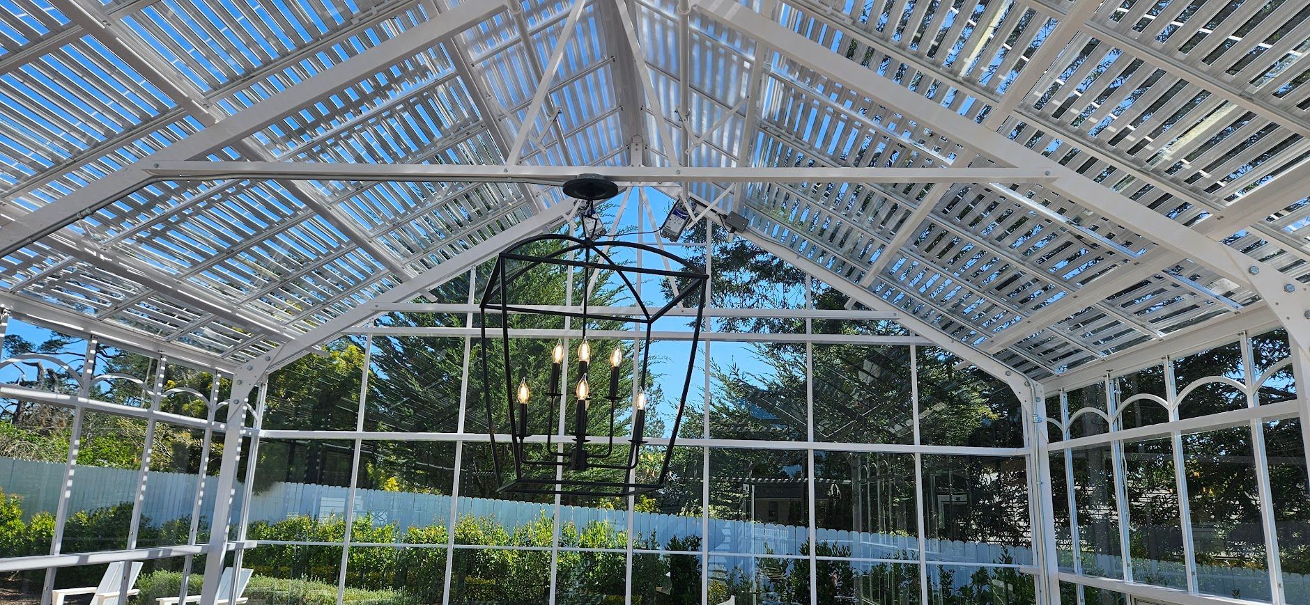 The inside of a greenhouse with a chandelier hanging from the ceiling.