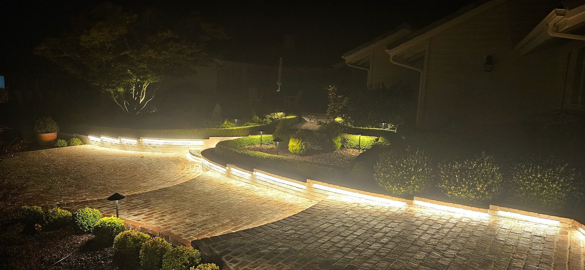 A driveway with lights on it is lit up at night.