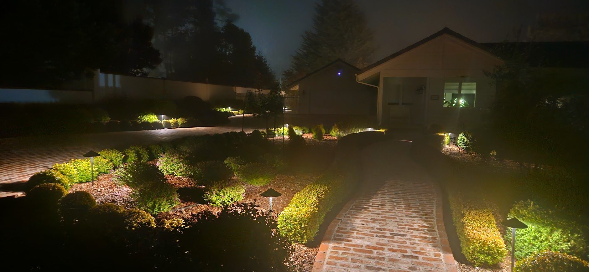 A house is lit up at night with a path leading to it.