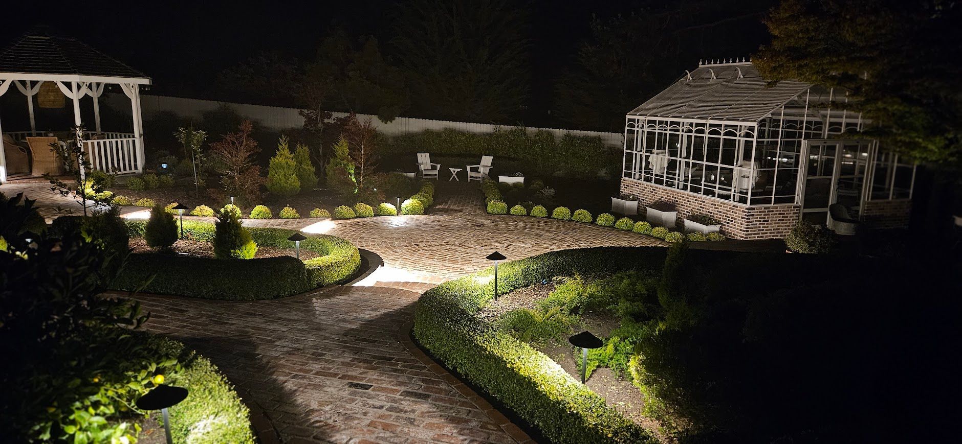 A gazebo is lit up at night in a garden.