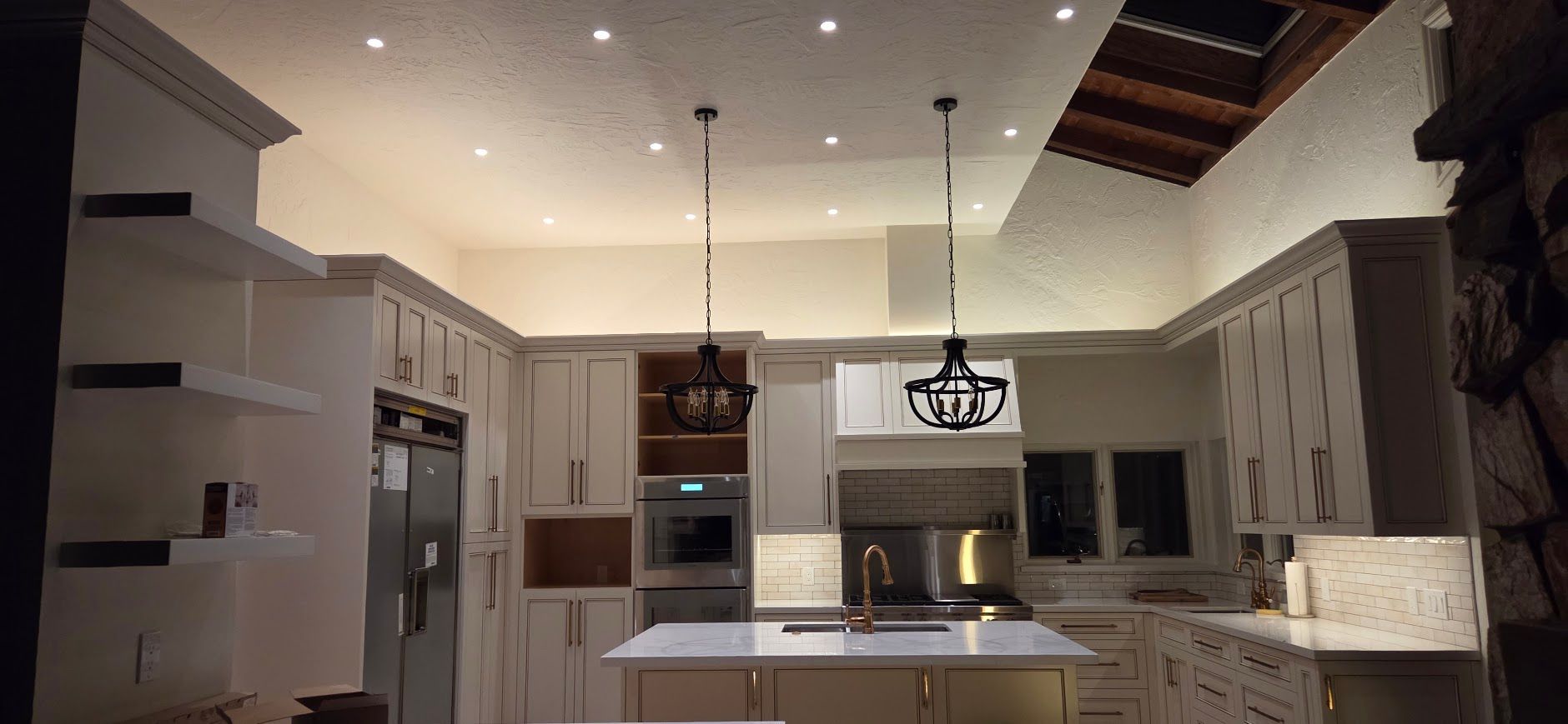 Modern kitchen with white cabinets, island, pendant lights, and stainless steel appliances