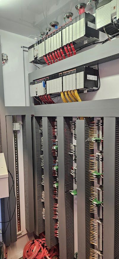 Server rack with rows of network hardware, cables, and blinking indicator lights in a data room