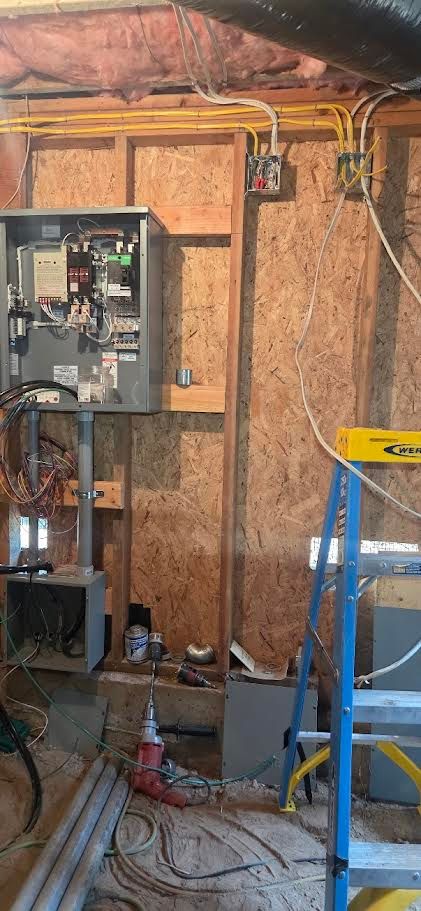 Basement utility room with open electrical panel, exposed wiring, and a blue ladder beside it.