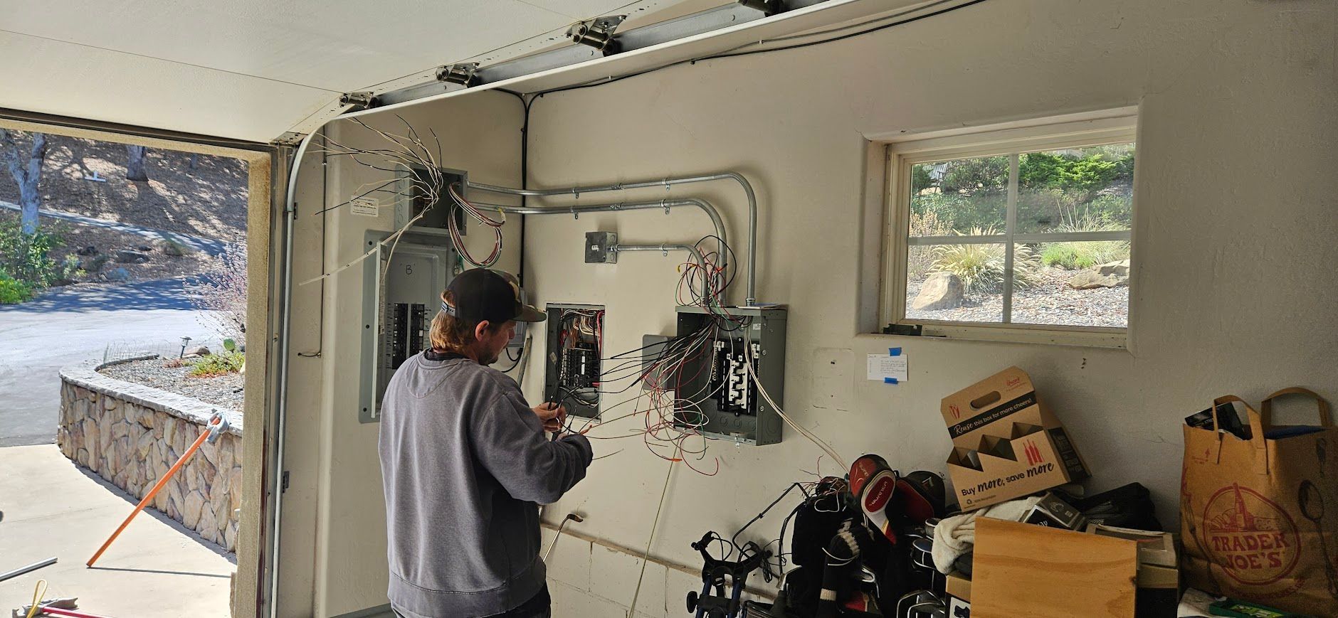 A man is working on an electrical box in a garage.
