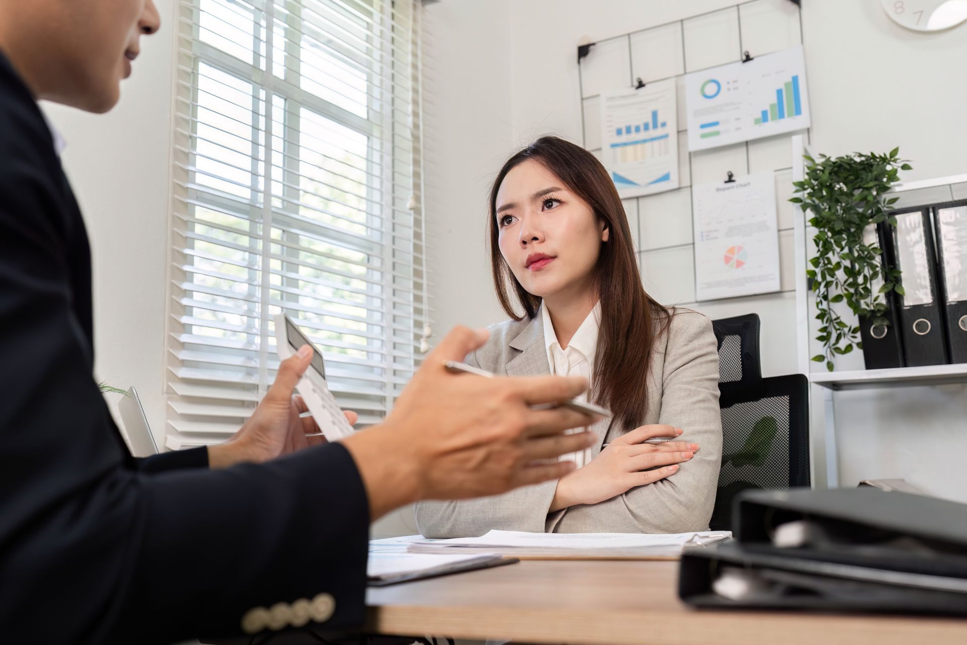 Two people in a bright office discussing documents across a desk.