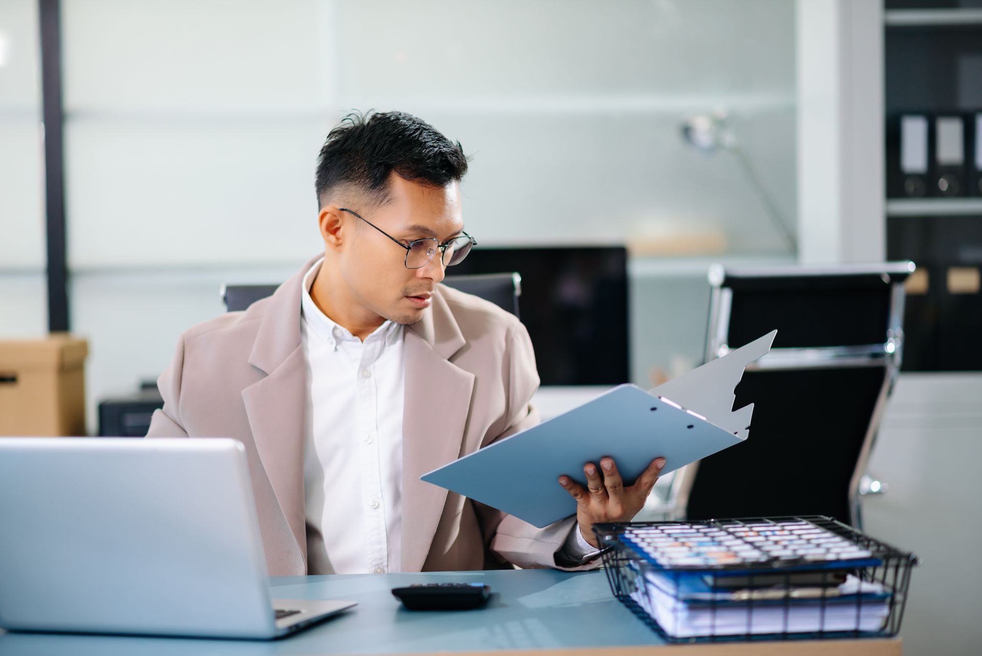 Person reviewing documents at a desk beside a laptop in a bright office