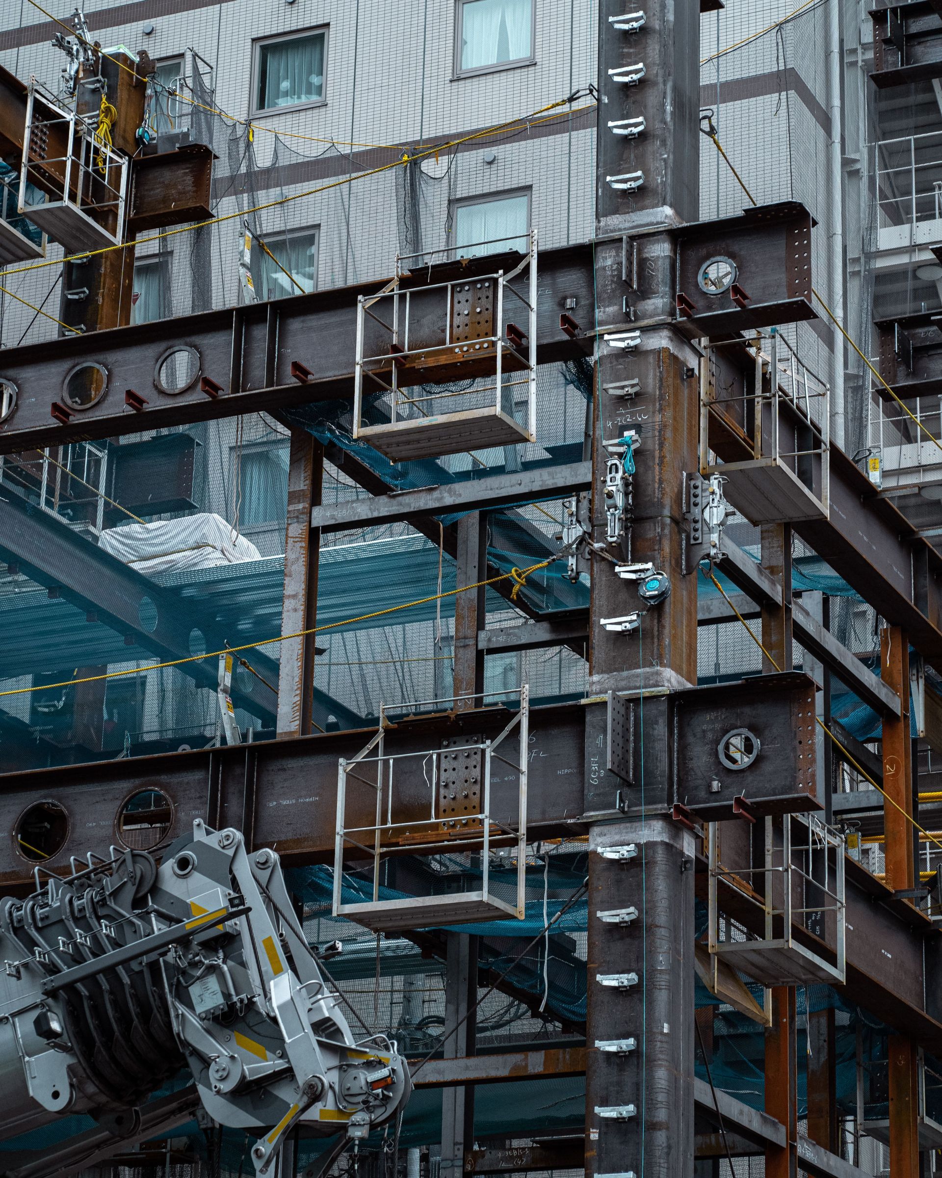 Industrial structure with steel beams, pipes, and hanging platforms on a weathered building facade