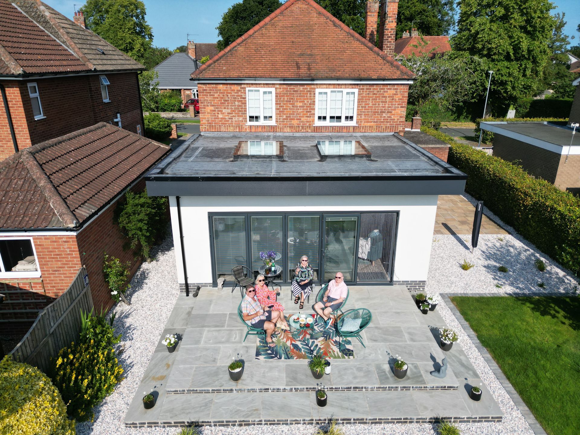 A group of people are sitting on a patio in front of a house.