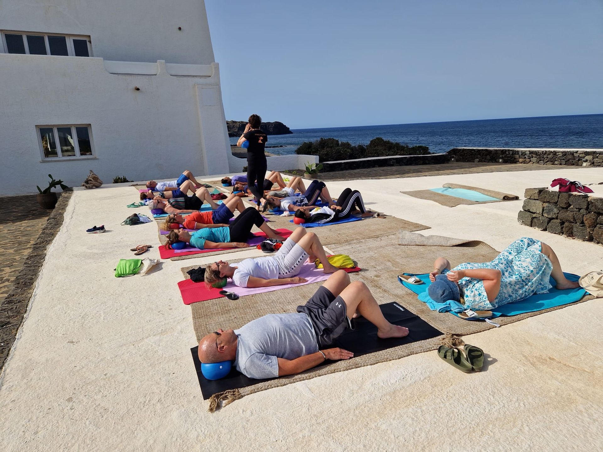 Lezione di yoga di gruppo all'aperto, in riva al mare.