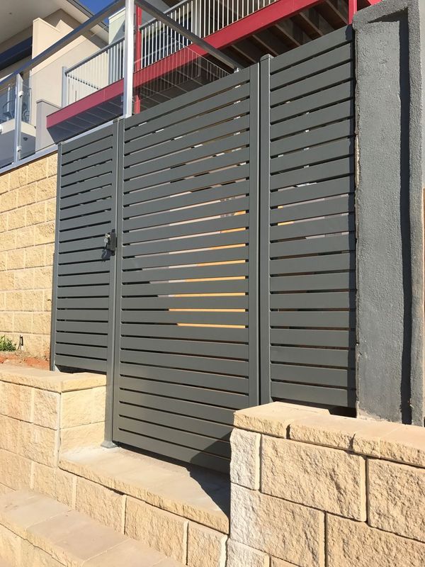 A fence with a gate and a brick wall in front of a house.