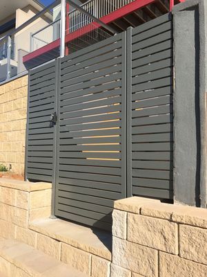 A fence with a gate and a brick wall in front of a house.