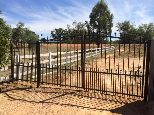 A wrought iron gate with a fence in the background