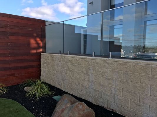 A brick wall with a glass railing and a wooden fence.
