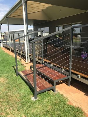A wooden deck with a metal railing and stairs leading up to it.
