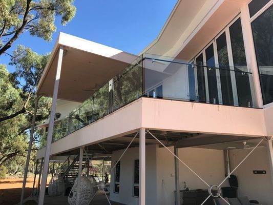 A large white house with a balcony with a glass railing