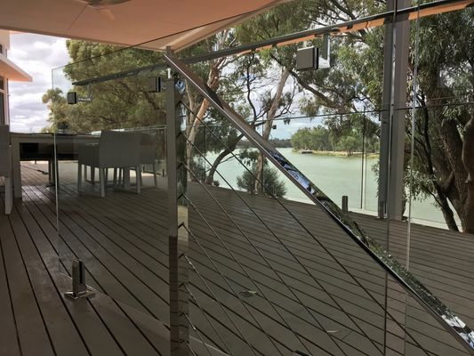 A glass railing on a deck overlooking a body of water.