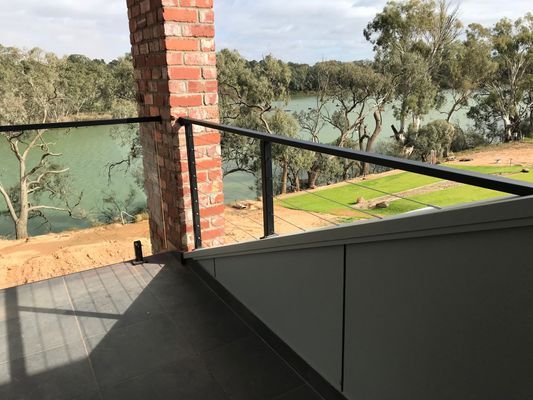 A balcony with a view of a lake and trees.