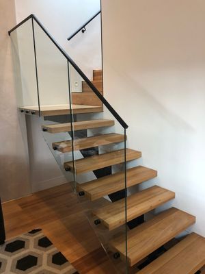 A wooden staircase with a glass railing in a room.