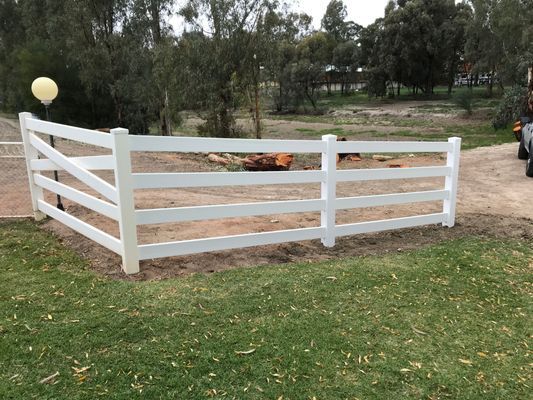 A white fence is sitting on top of a lush green field.