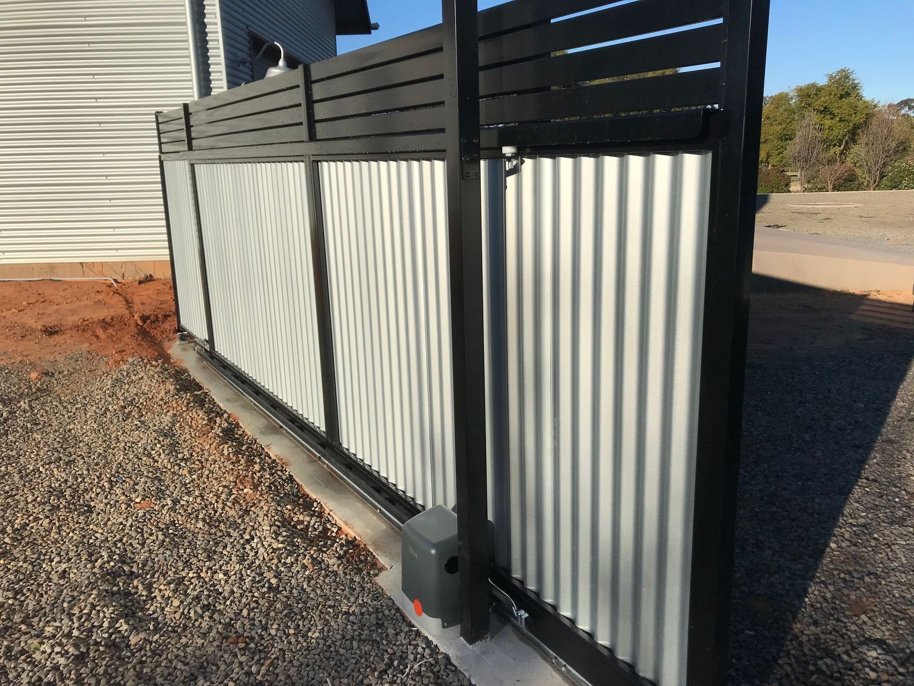 A white and black fence with a black sliding gate