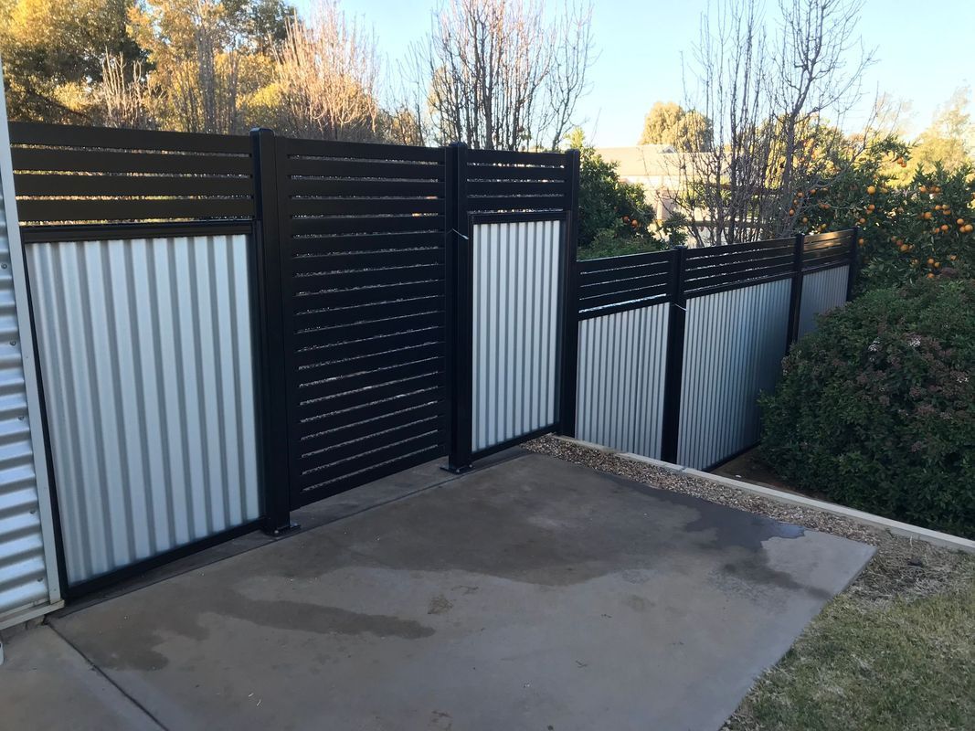 A black and white fence is surrounding a concrete area.