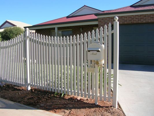 A white picket fence with a mailbox in front of a house