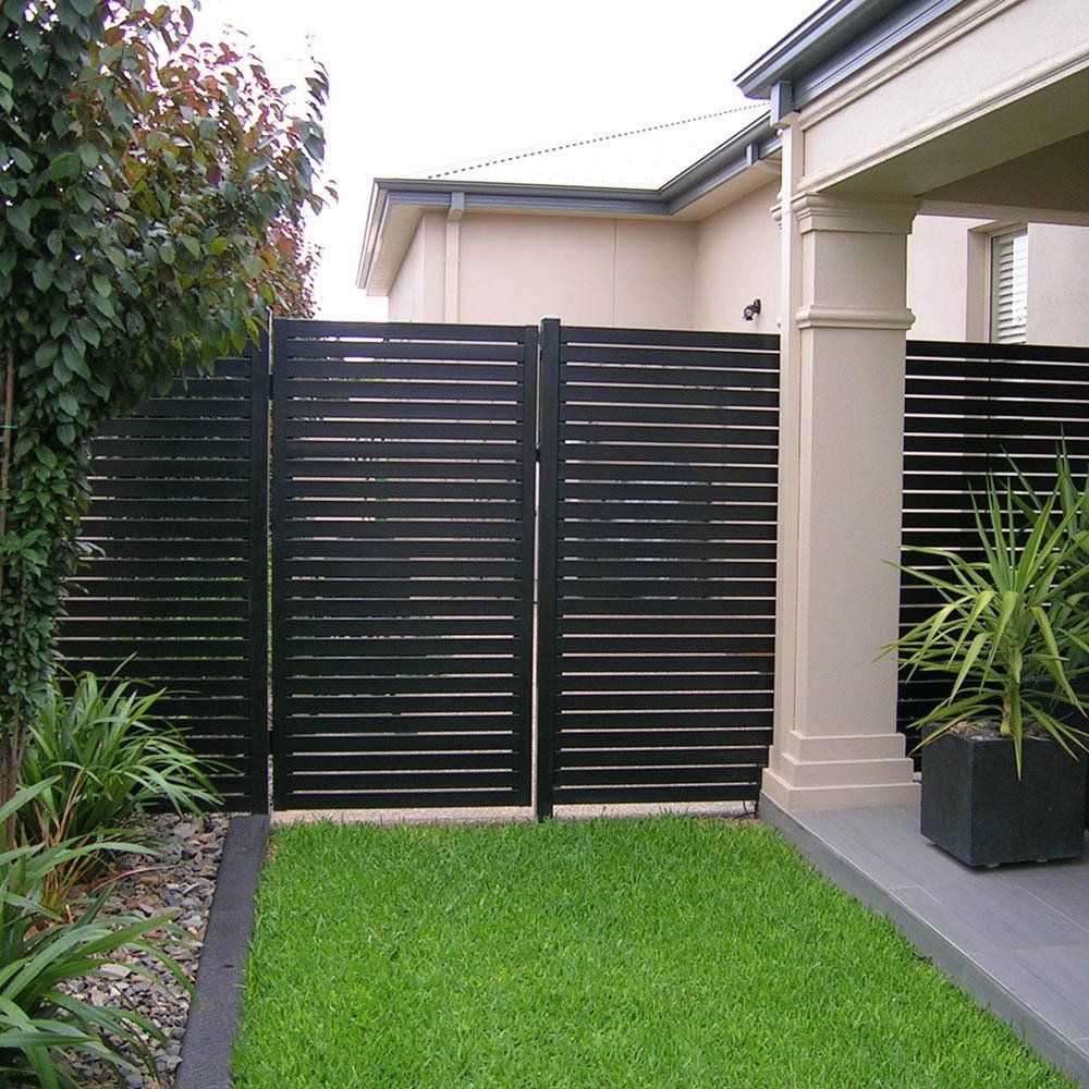 A black fence surrounds a lush green yard in front of a house
