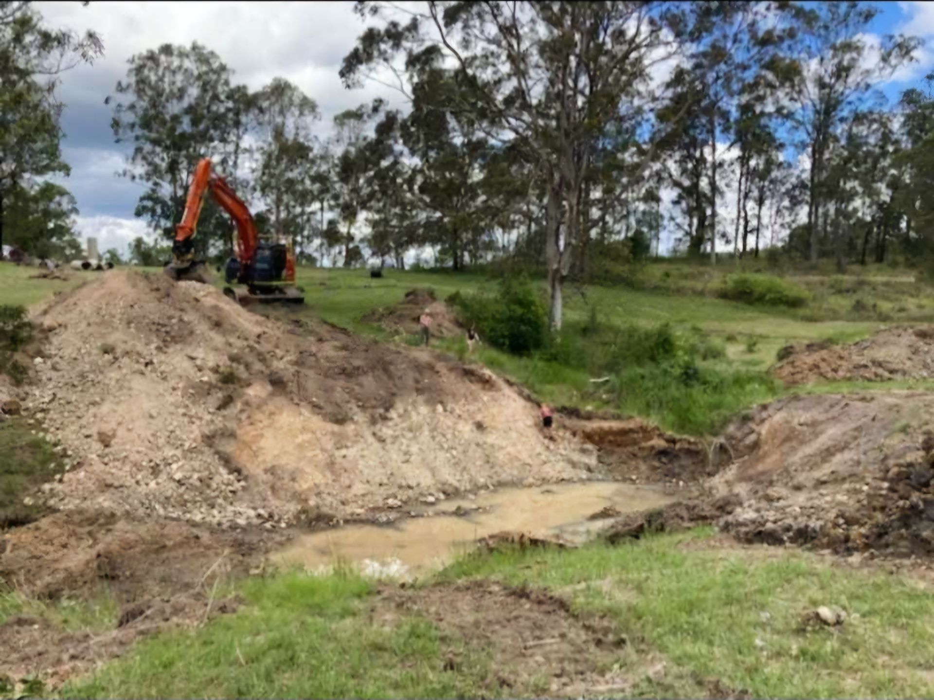 Dam construction with orange digger in background— CHT Excavation and Hire In Wherrol Flat NSW