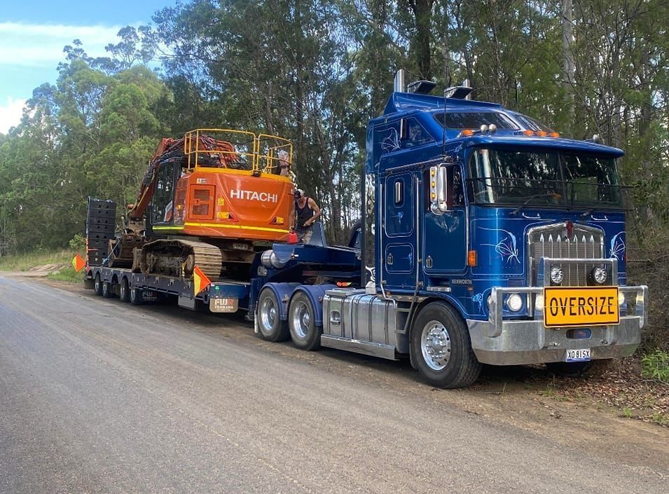 Grader Tractor On Transportation Trailer Truck On The Highway — CHT Excavation and Hire In Wherrol Flat NSW