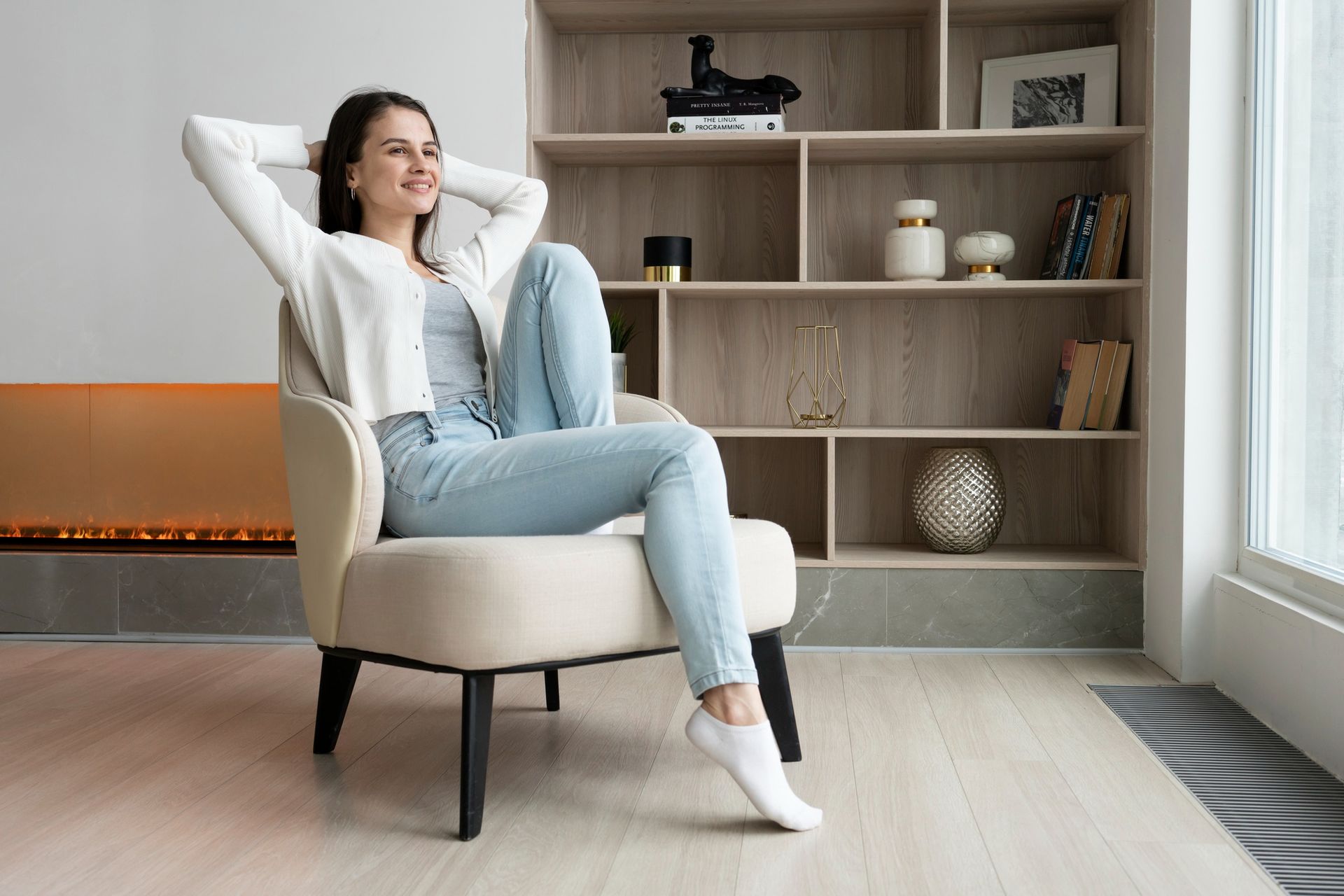 A woman is sitting in a chair with her legs crossed in a living room.
