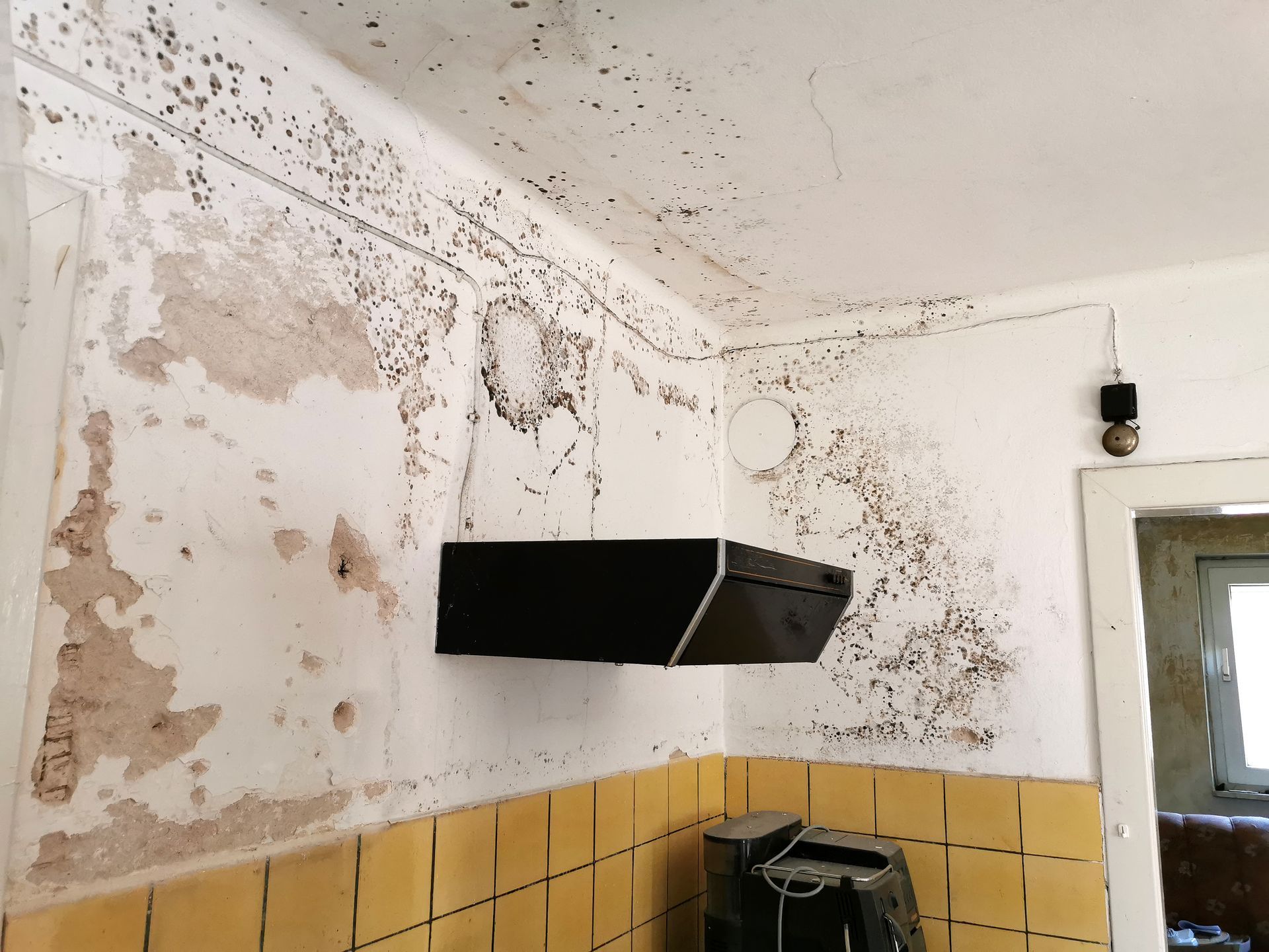 A kitchen with yellow tiles and a black hood.