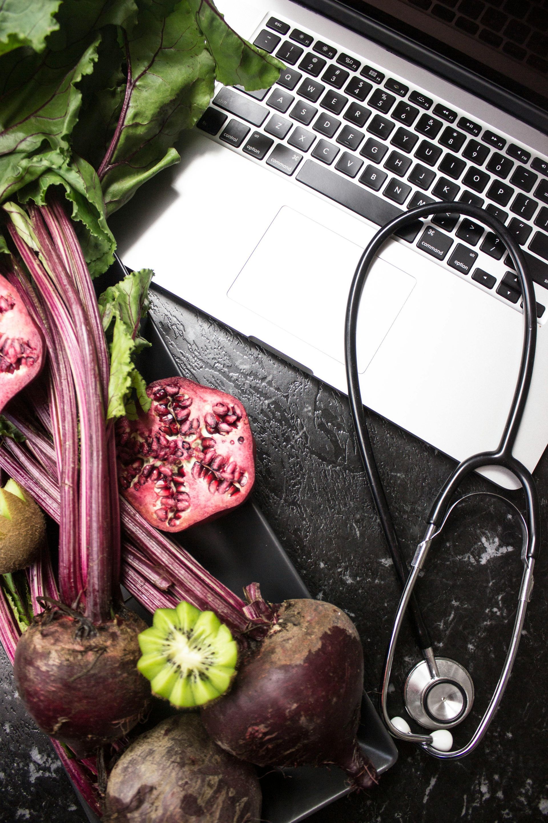 A stethoscope is sitting on a table next to a laptop.