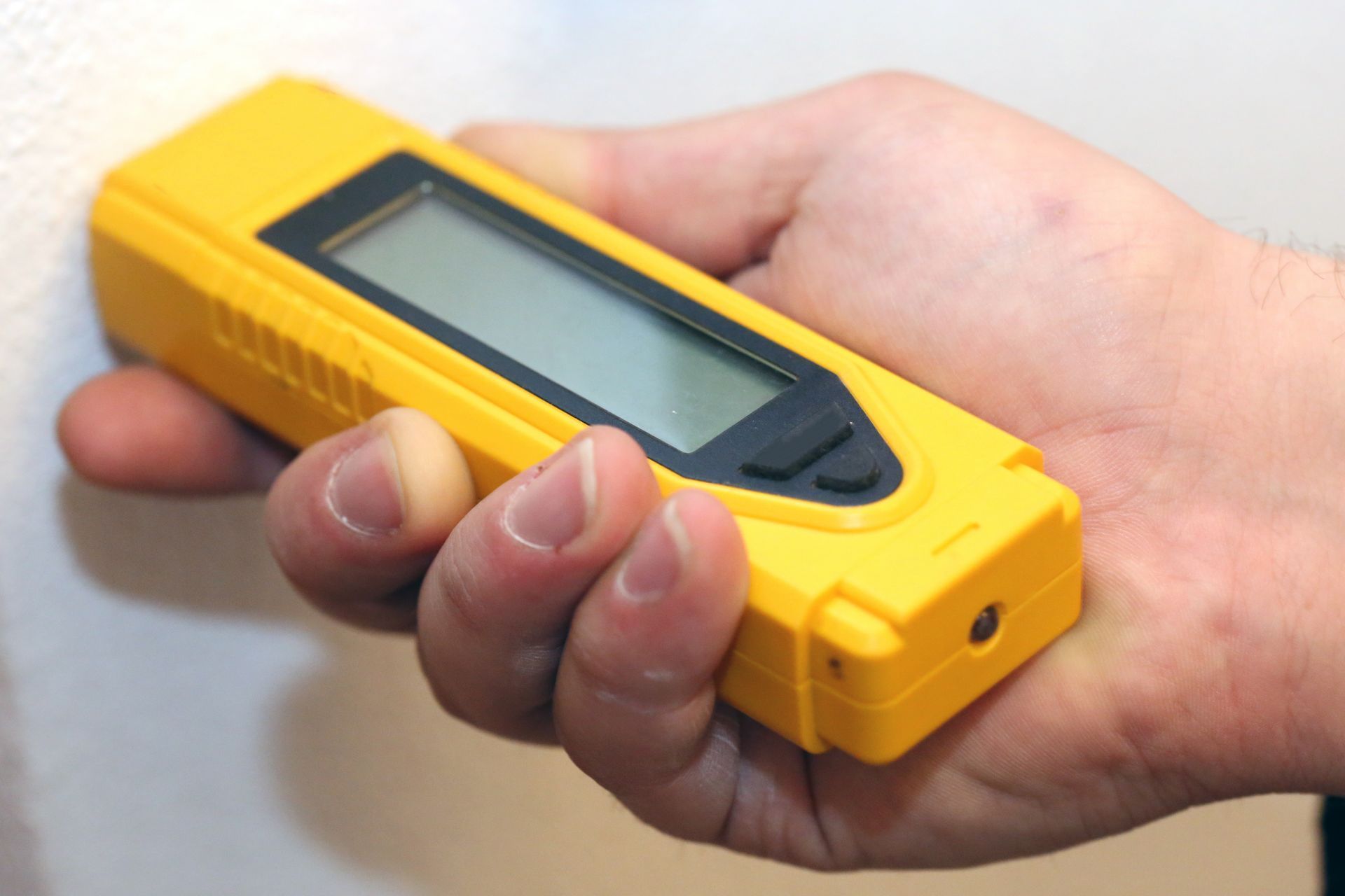 A person is holding a yellow device in their hand.