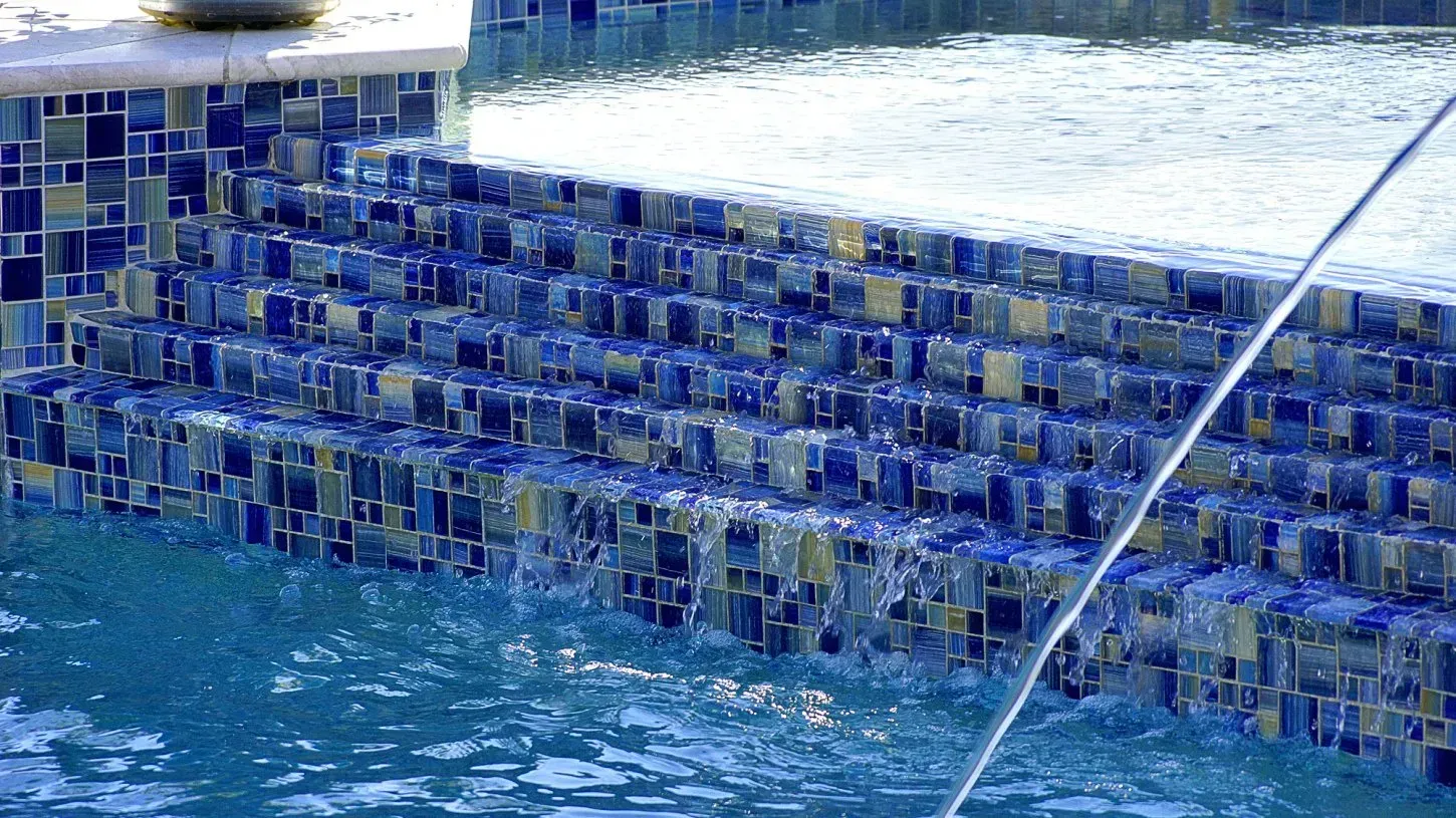Blue tiled pool steps with water flowing over them.