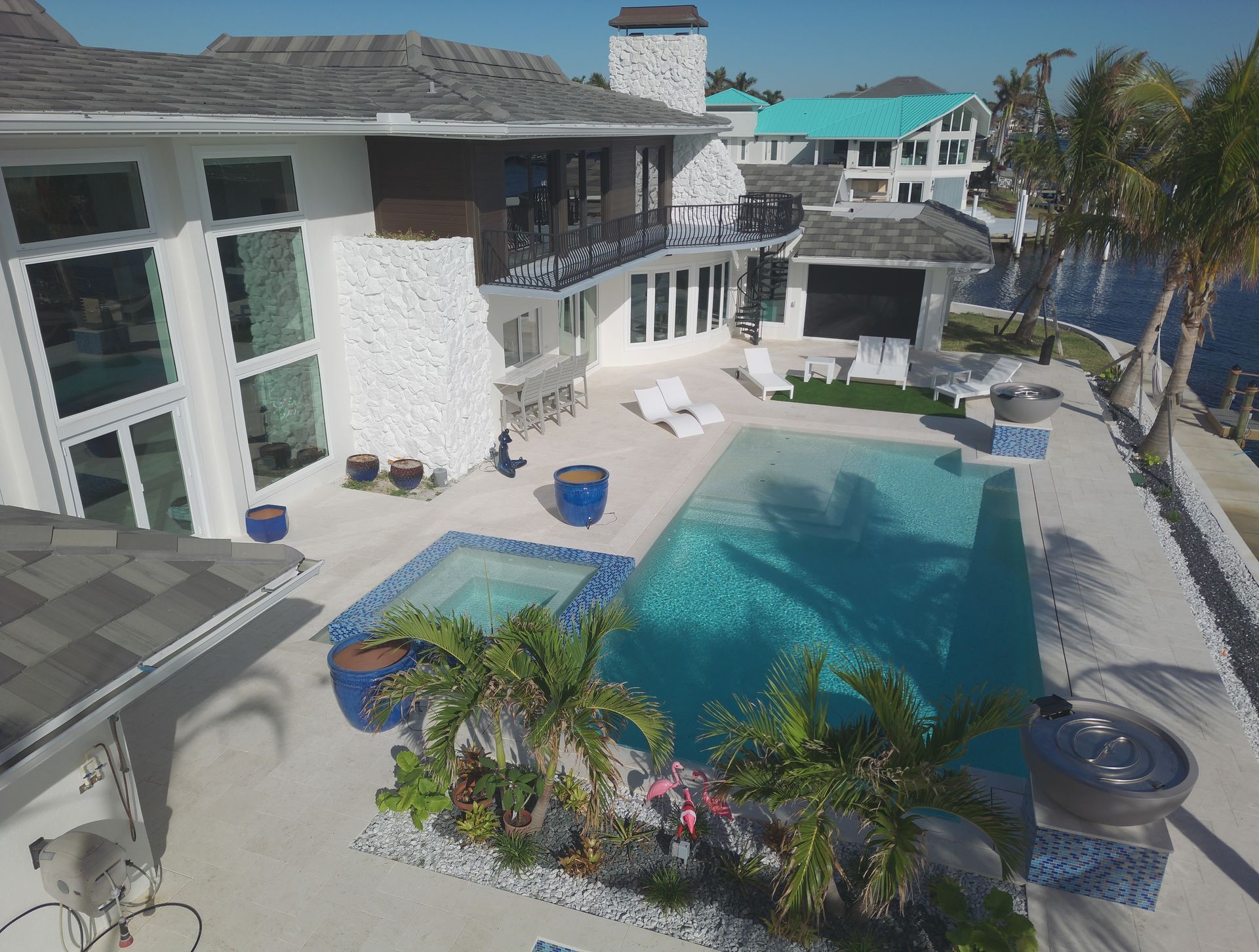 Luxury waterfront home with a pool, hot tub, and palm trees.