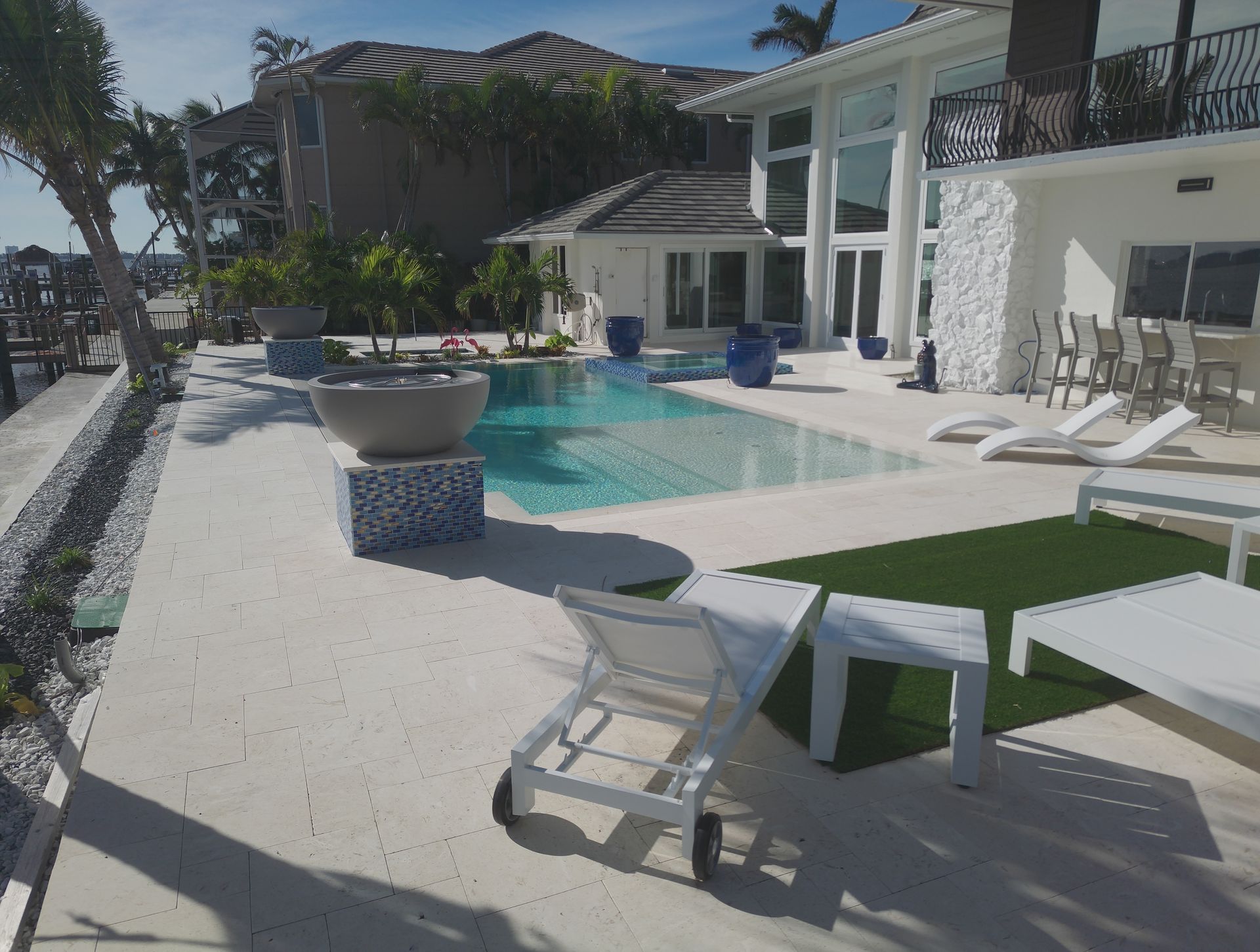 A luxurious pool and patio area with lounge chairs beside a white modern house.