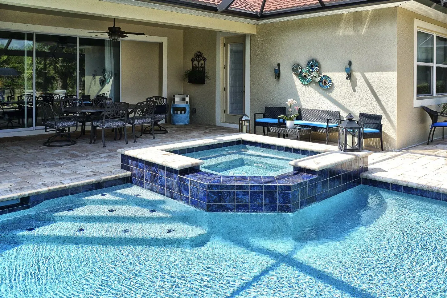 Backyard with a pool and hot tub, patio furniture, and a stucco exterior.