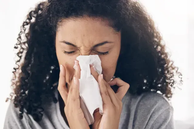 A woman is blowing her nose into a napkin.