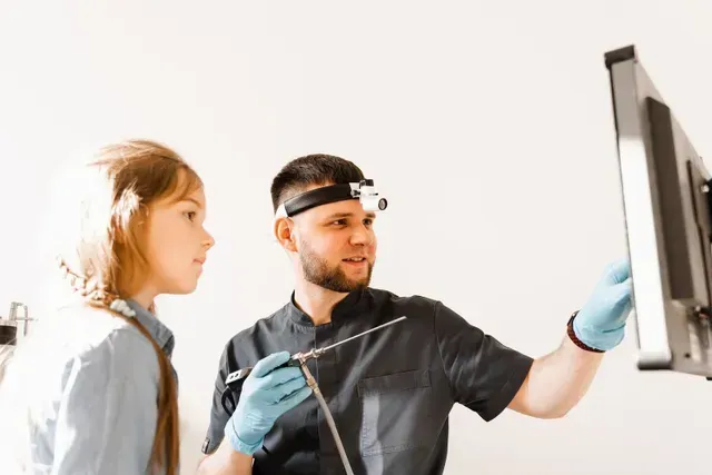 A rhinologist pointing the monitor to a pediatric patient