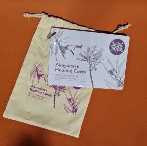 A set of Akeyulerre Healing Cards in a matching drawstring bag against an orange background.
