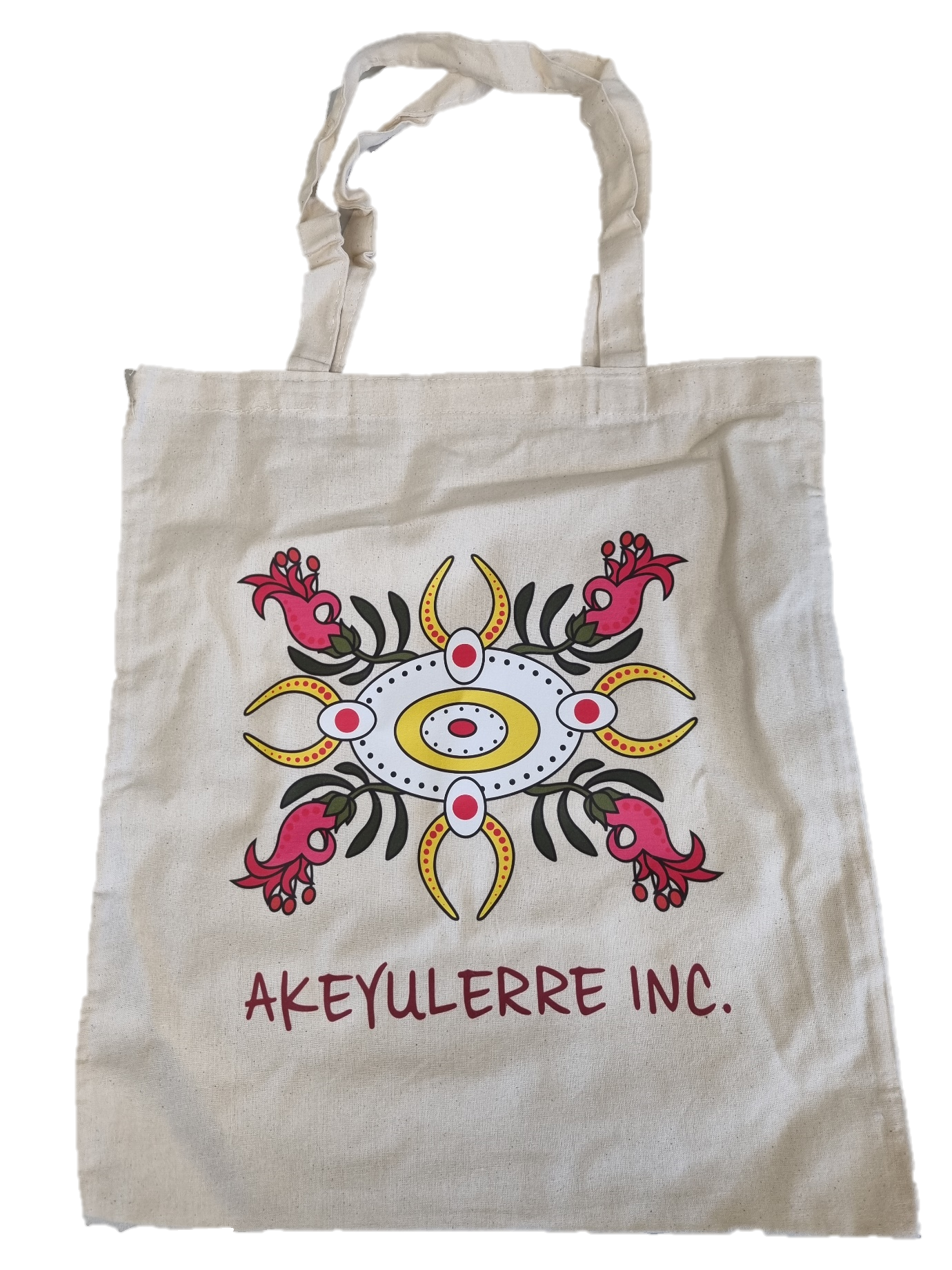 A beige canvas tote bag printed with a colorful, symmetrical botanical design and the text "AKEYULERRE INC."