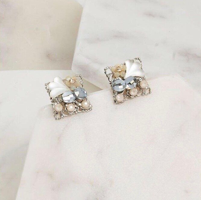 A pair of earrings are sitting on a white surface.