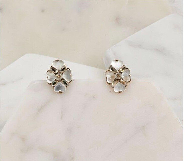 A pair of earrings are sitting on a white surface.