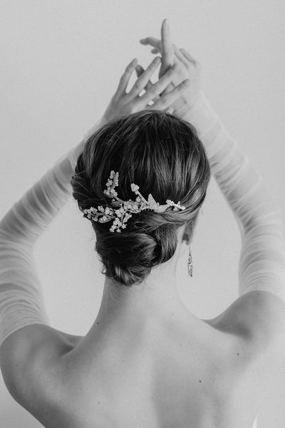 A black and white photo of a woman adjusting her hair.