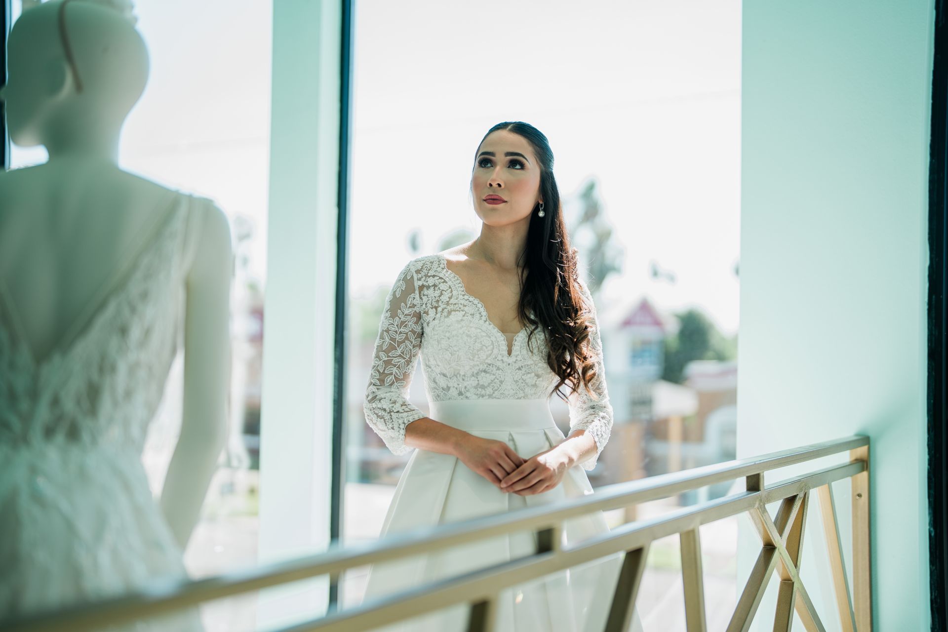 A woman in a wedding dress is standing in front of a window.