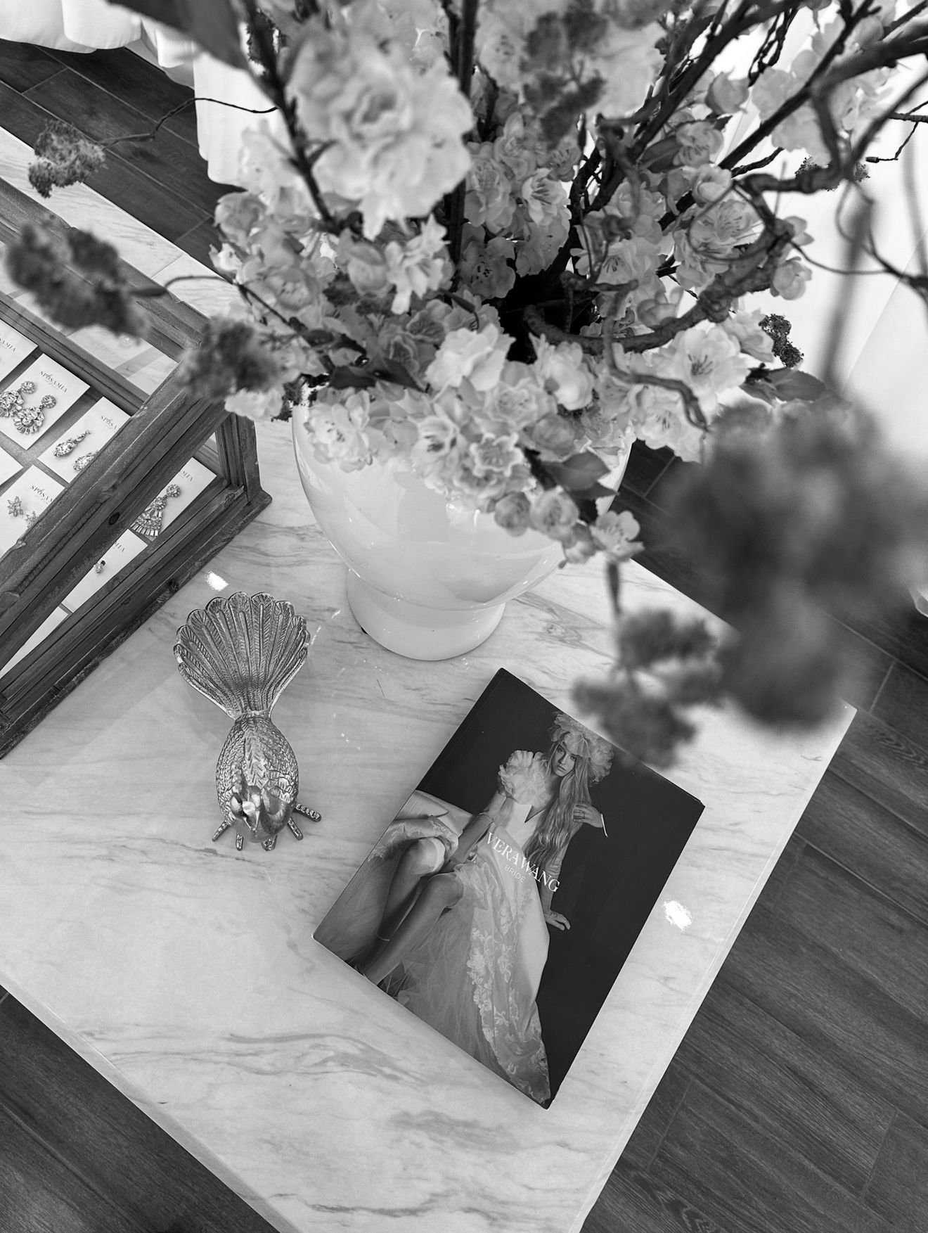 A black and white photo of a vase of flowers on a table.