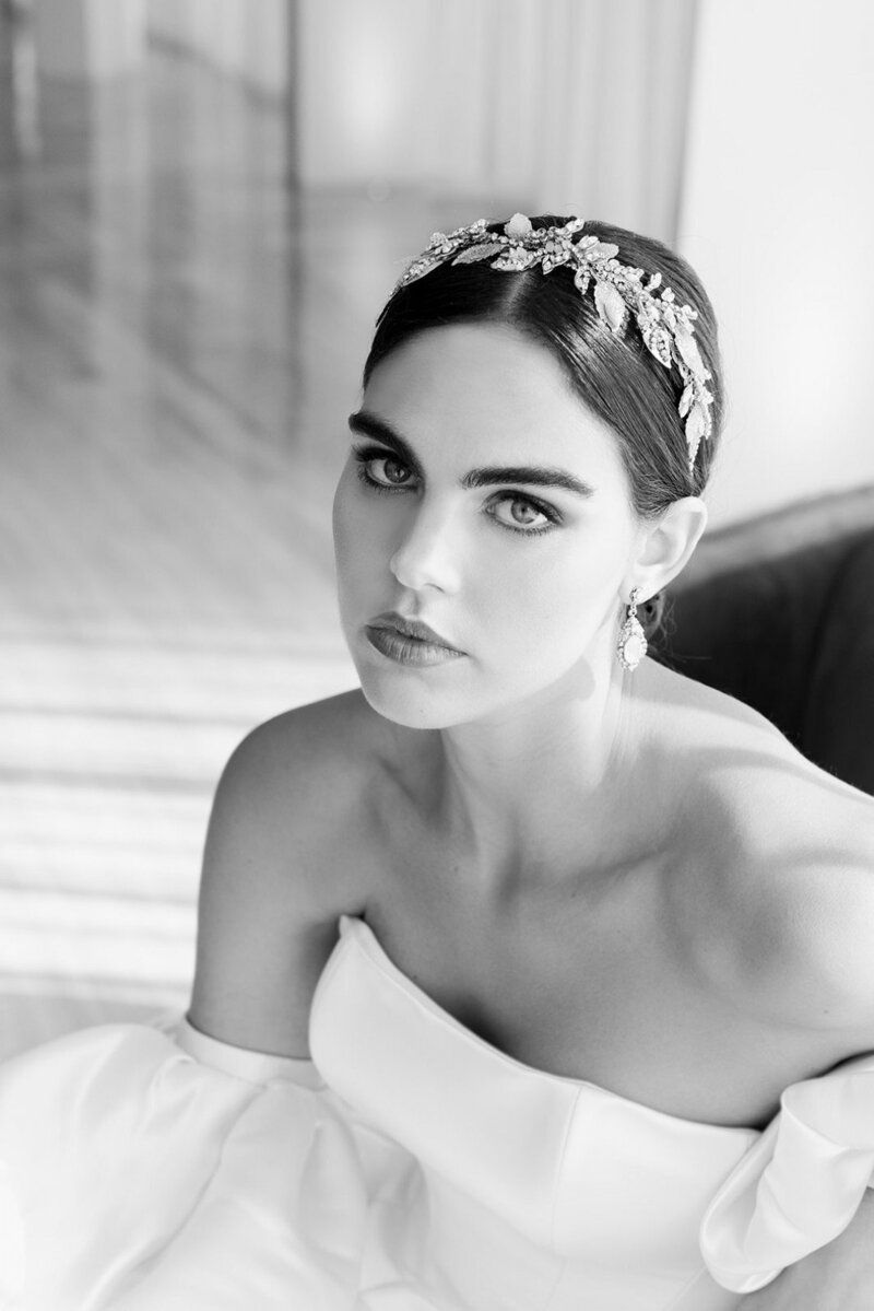 A black and white photo of a woman in a wedding dress wearing a headband.