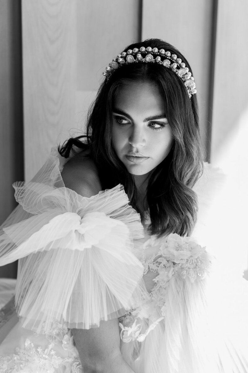 A black and white photo of a woman in a wedding dress wearing a tiara.