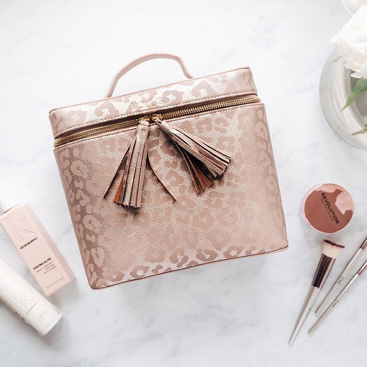 A leopard print makeup bag with tassels sits on a table